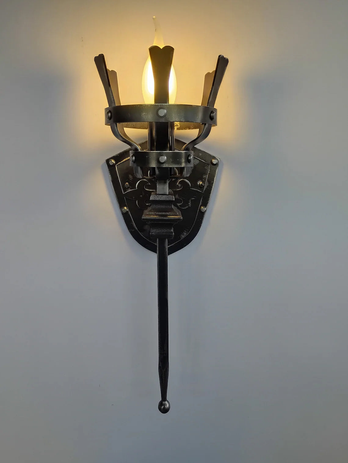 Decorative wall sconce with a long arm on a plain background