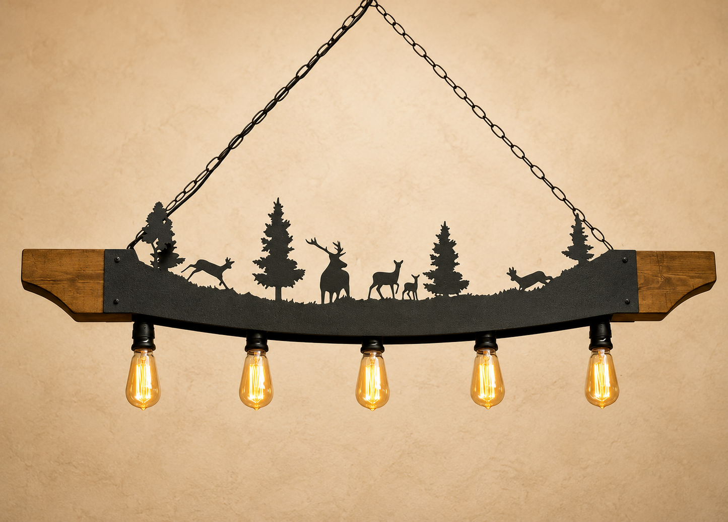 A rustic hanging light fixture with a curved wooden bar, black metal silhouette of deer and trees, and five glowing warm Edison bulbs against a beige textured background.