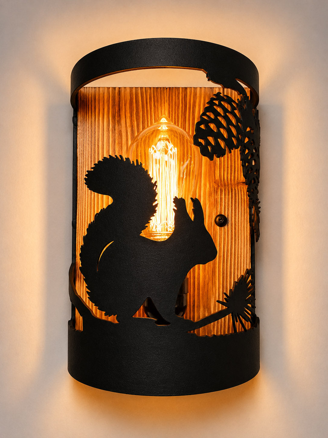 Handcrafted squirrel wall light featuring a laser-cut steel squirrel beneath a pine branch with a solid wood back panel for rustic cabins, cottages, and woodland homes.