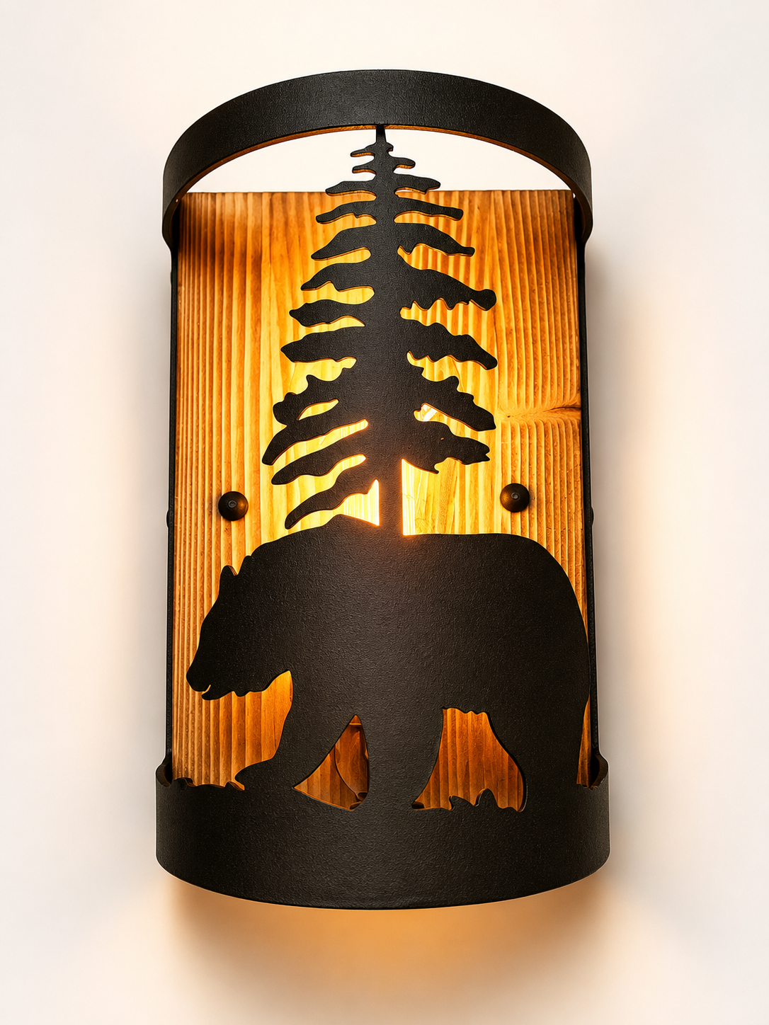 A semi-cylindrical wall sconce light fixture with a black metal frame featuring a silhouette of a bear and a pine tree over a warm, vertically slatted wood panel.