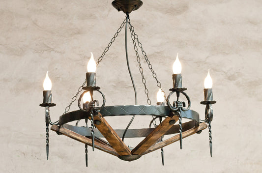 A rustic chandelier featuring wrought iron with a hammered black finish, and elements that resemble wood staves.