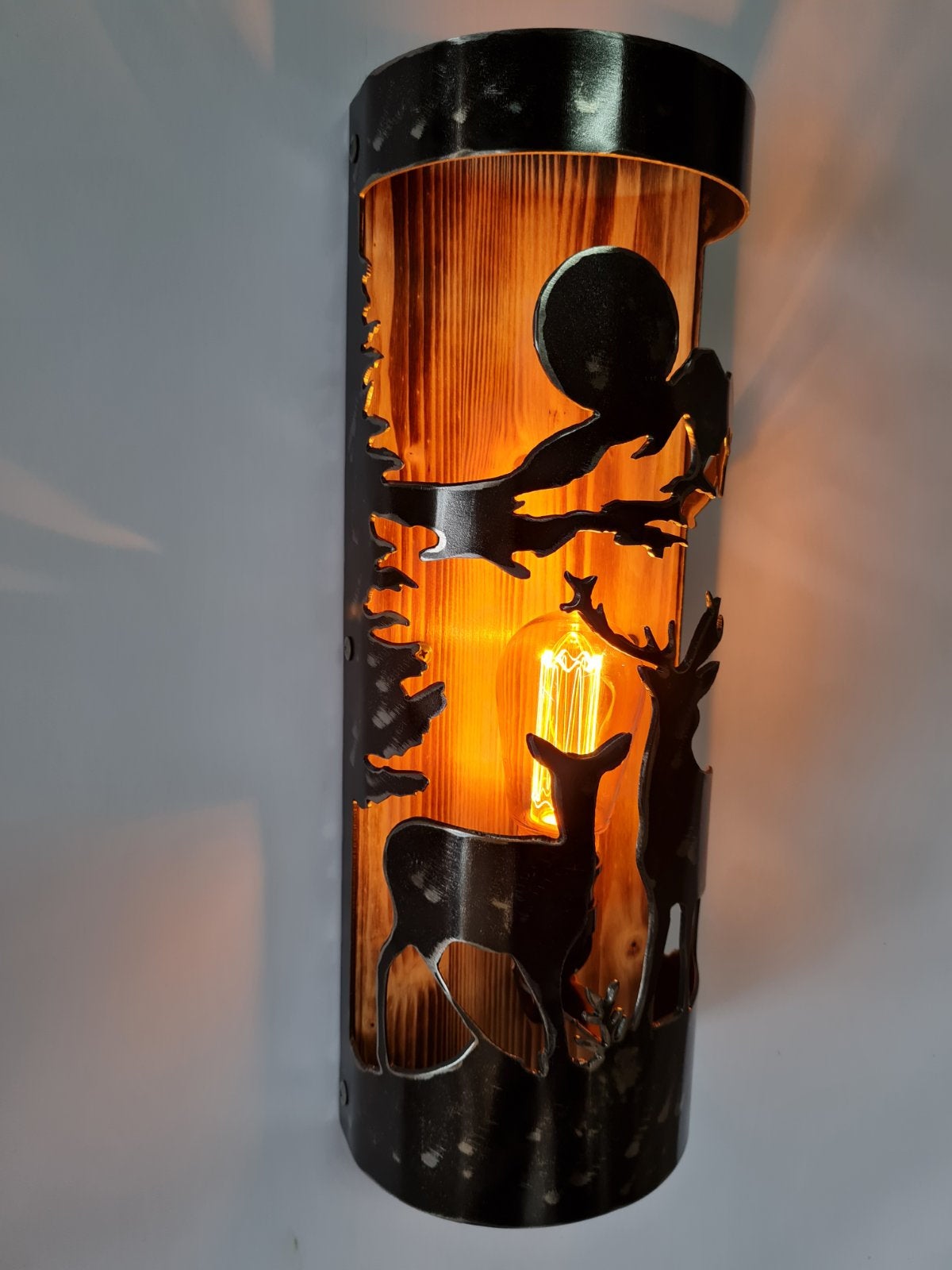 Buck and doe cabin sconce casting warm amber glow, log house wall light