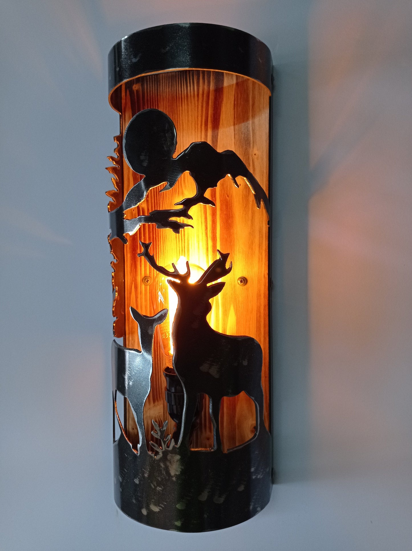 Wildlife wall sconce with hand-brushed steel shade and charred wood backplate