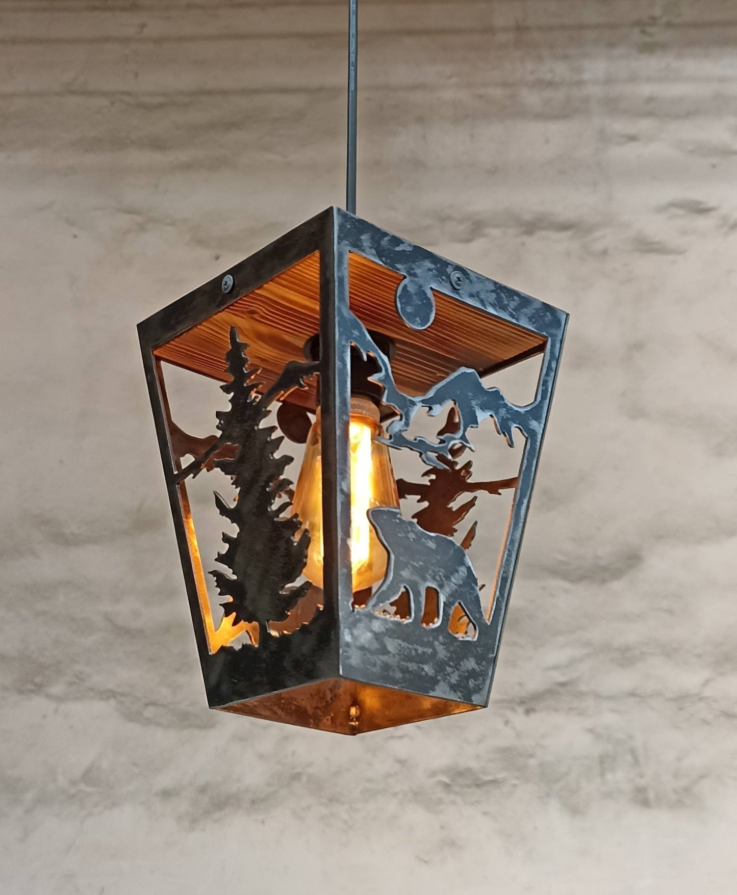 Rustic pendant light with a metal frame and a clear varnish finish, featuring a cut-out design of bears and trees in a cabin-style ceiling light.