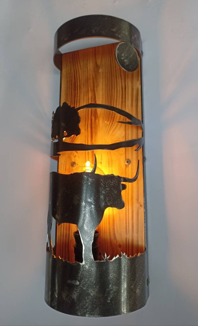 Longhorn steel silhouette wall sconce on charred wood backplate, rustic interior lighting