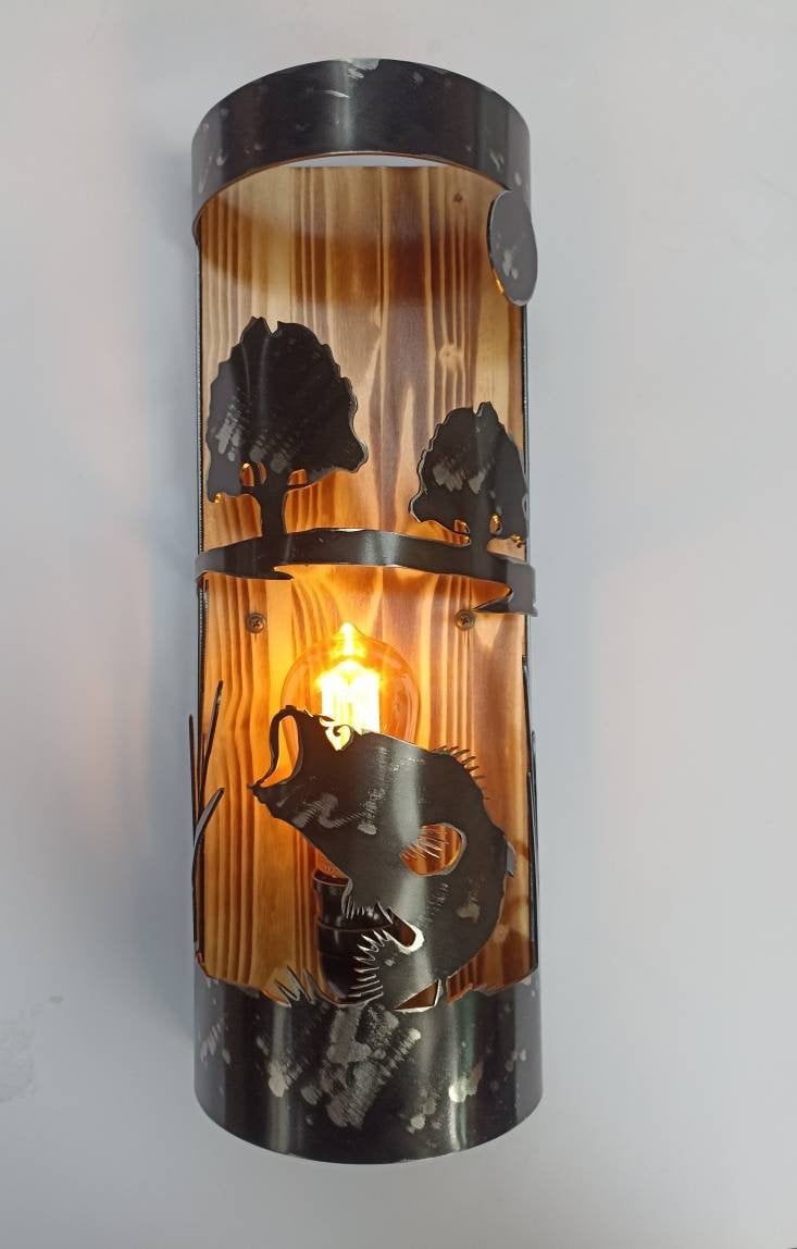 A rustic style wall light with a bass fish theme, featuring an amber glow, encased in a cylindrical structure with a black finish and decorative elements.