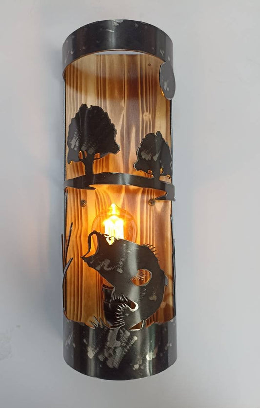 A rustic style wall light with a bass fish theme, featuring an amber glow, encased in a cylindrical structure with a black finish and decorative elements.