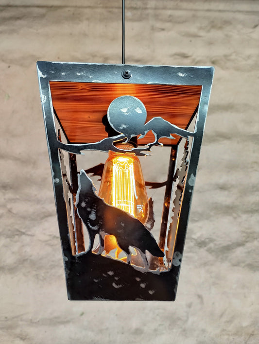 Rustic pendant light with a wolf theme, made of wood and steel with a clear varnish coating, hanging against a wooden background.